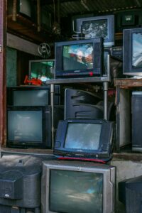 A stack of vintage televisions displayed at a street market, showcasing various models.
